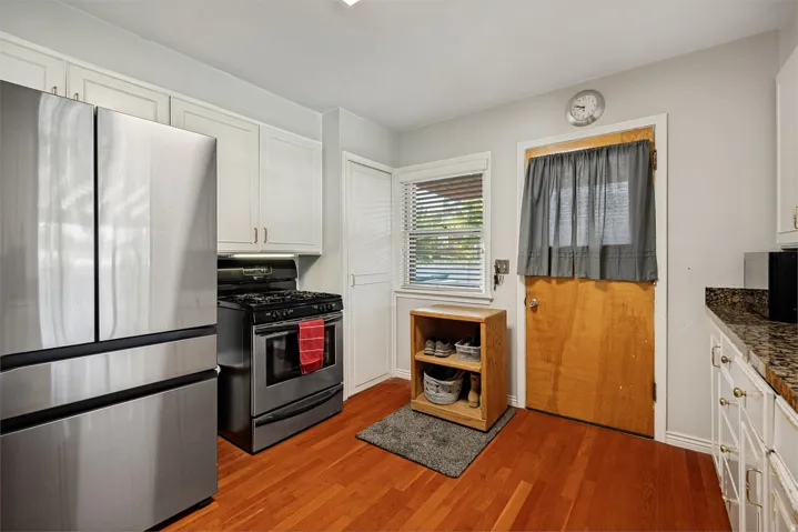 Kitchen featuring wood-finish flooring, white cabinetry, stainless steel appliances, and stone-finish countertops