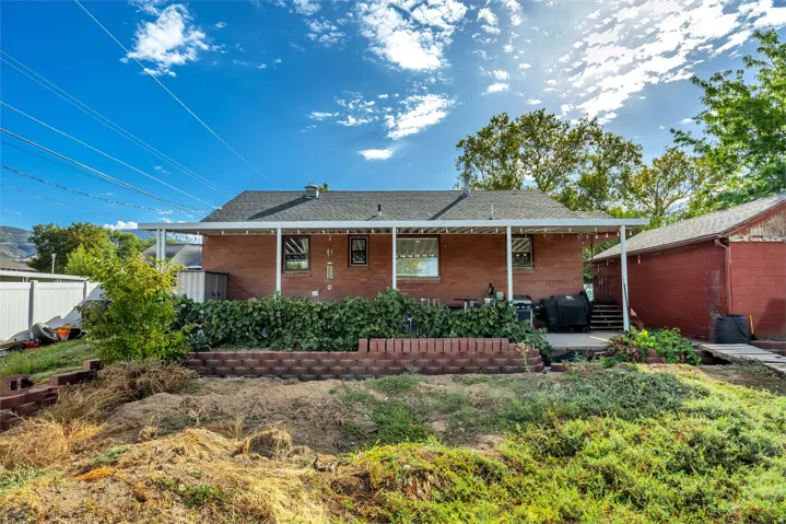 Brick exterior with covered patio, concrete patio surface, and a retaining wall
