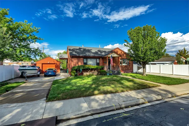 Brick exterior, asphalt shingle roof, concrete driveway, detached garage, and mature landscaping