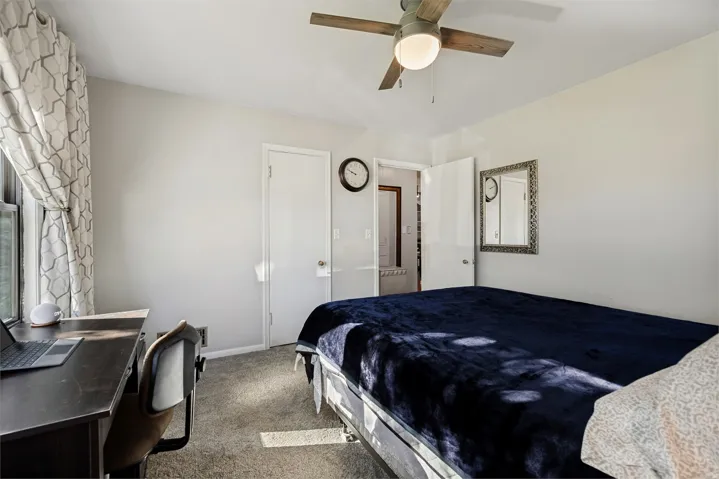 Room featuring neutral wall tones, wood-finish ceiling fan, and carpeted flooring
