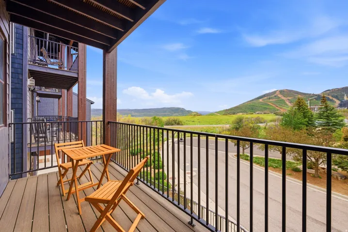 Private balcony featuring composite decking, black metal railings, and wood-clad structural columns