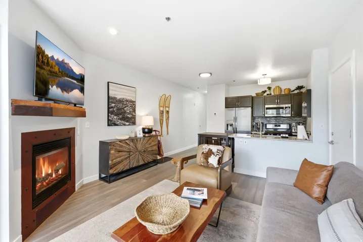 Fireplace with a wood mantle, wood-finish flooring, recessed lighting, ceiling-mounted light fixture, and stainless steel appliances