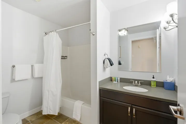 Bathroom featuring a built-in vanity with a flat-panel cabinet, integrated sink, and wall-mounted mirror