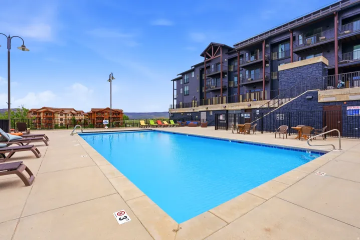 Outdoor swimming pool with integrated steps, concrete surround, and adjacent lounging area
