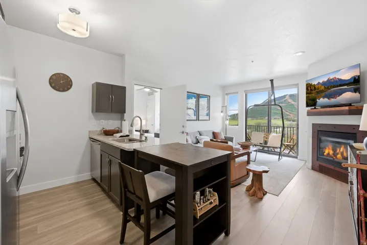 Open-concept living space with light wood-finish flooring, a contemporary fireplace, and a private balcony
