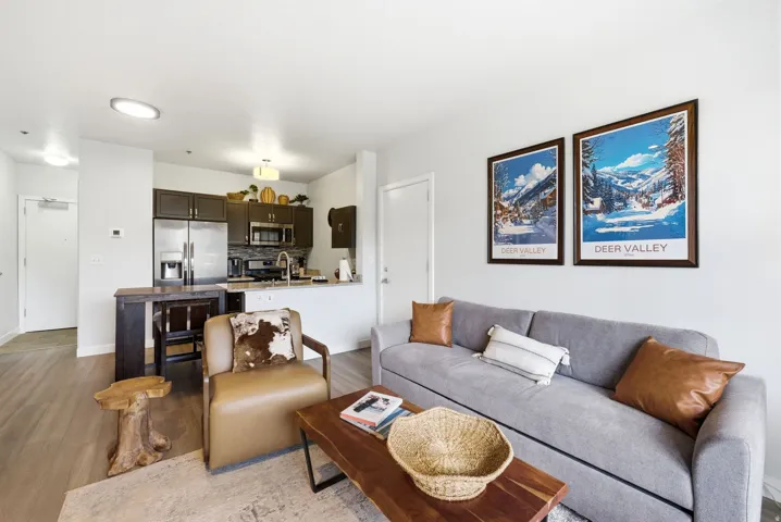 Open-concept living area featuring wood-finish flooring, recessed lighting, and a kitchen with dark cabinetry, stainless steel appliances, and a light-colored countertop