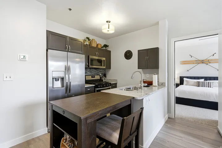 Stainless steel appliances, granite countertops, wood-finish flooring, dark wood cabinetry, and a subway tile backsplash