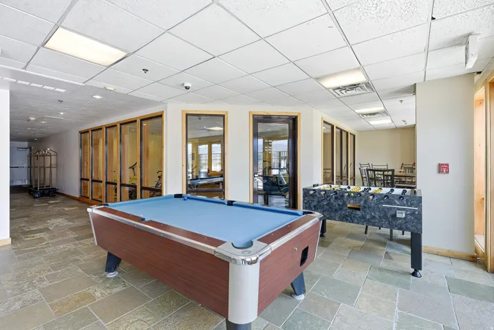 Recreational space with stone tile flooring, a billiards table, foosball table, and recessed ceiling lighting