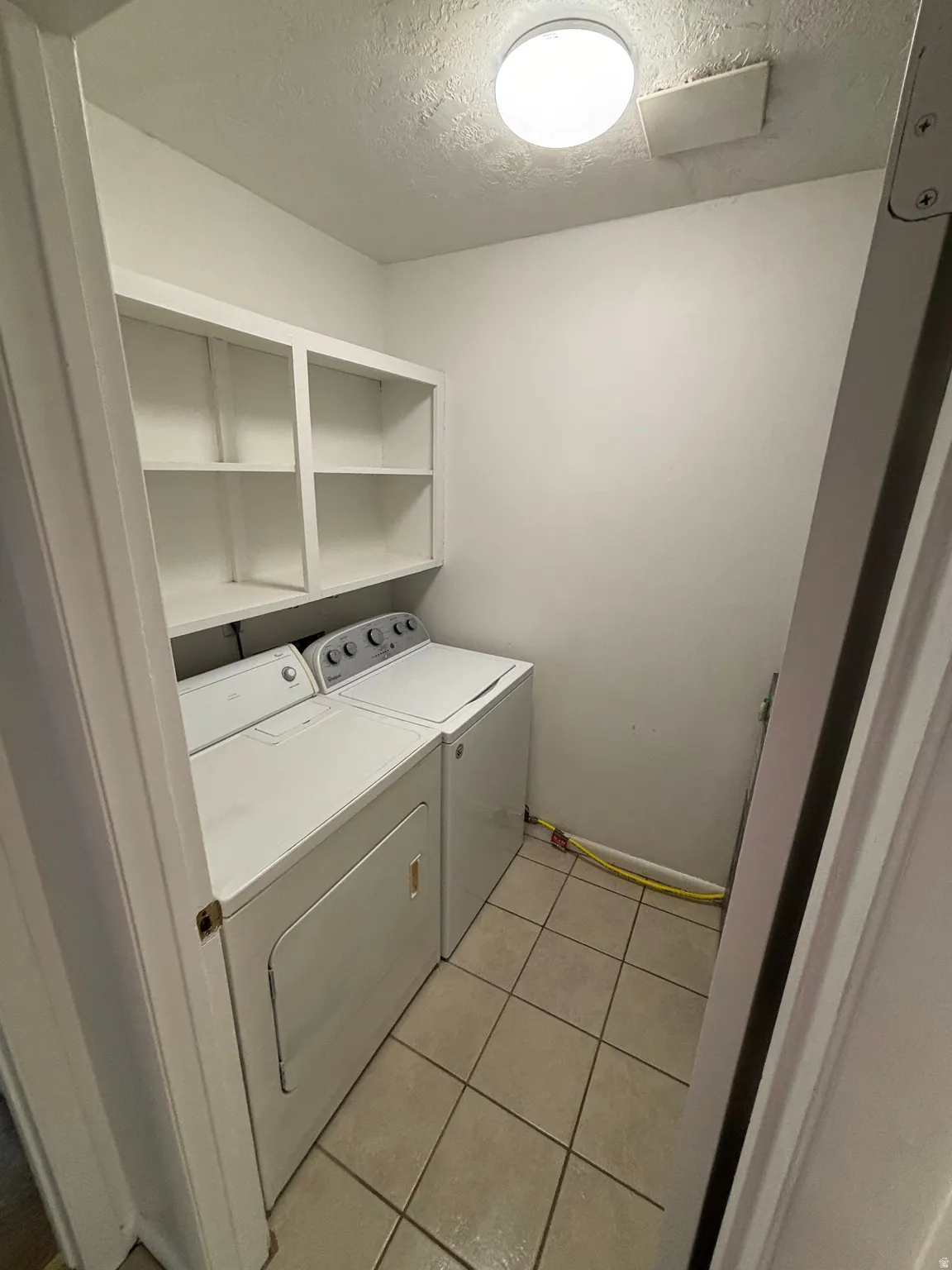 Built-in white shelving, tile flooring, and overhead lighting