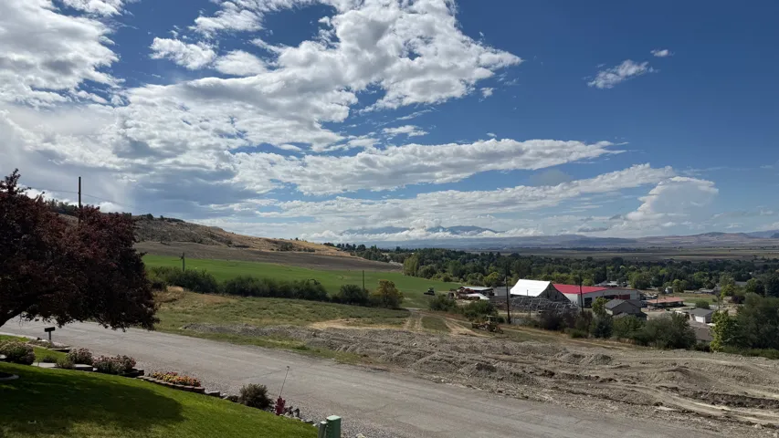 Expansive landscape featuring distant mountains, agricultural fields, and scattered structures under a wide sky