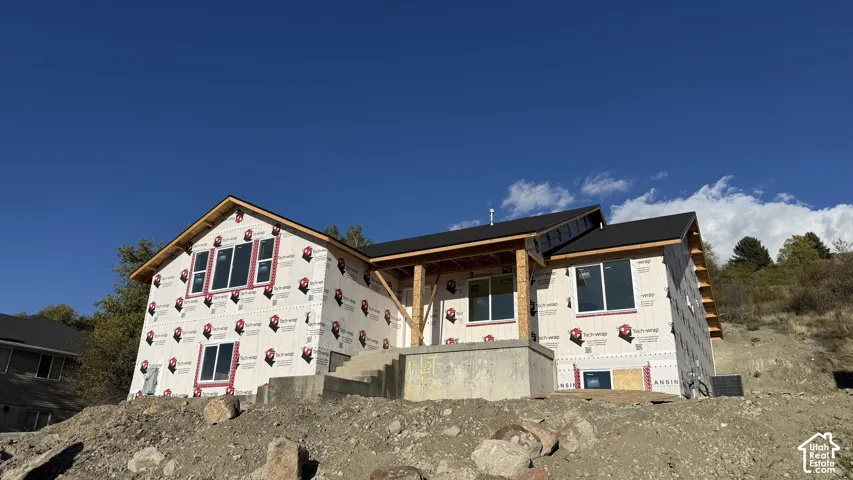 Single-story residential structure under construction featuring a gable roof, covered front porch with timber posts, and concrete steps