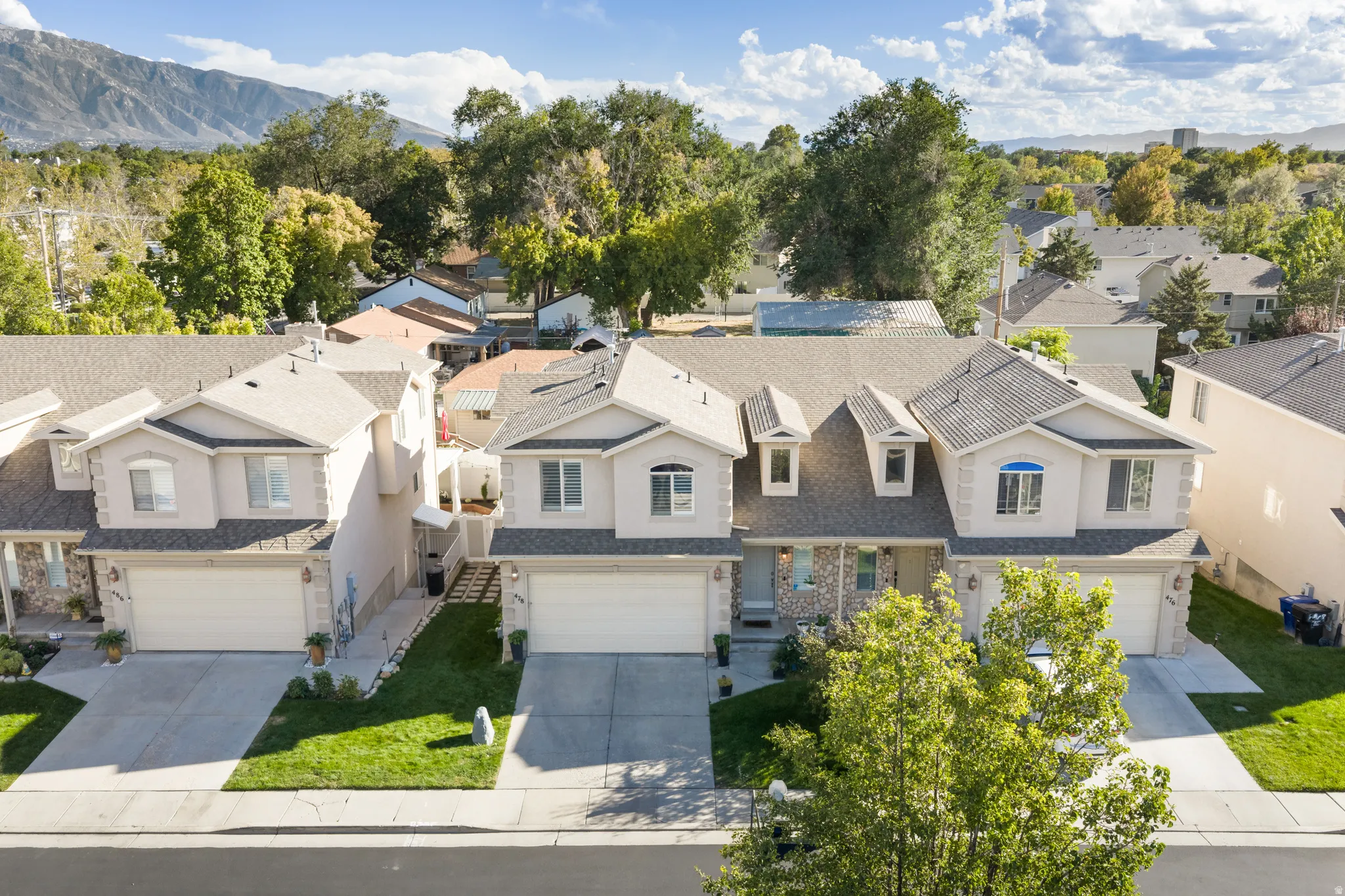 Two-story residential structures featuring attached garages, front driveways, and manicured lawns