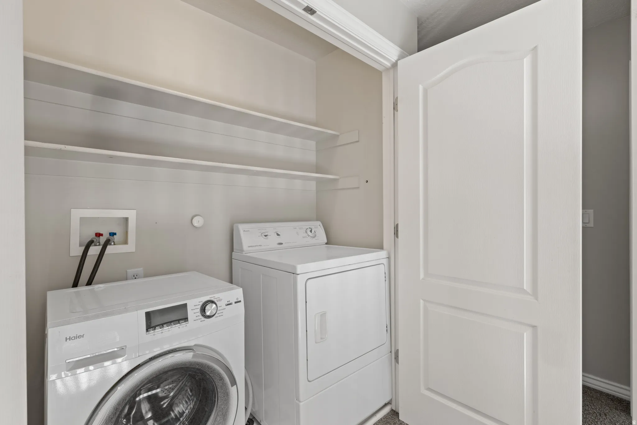 Laundry area with integrated shelving and included washer and dryer appliances