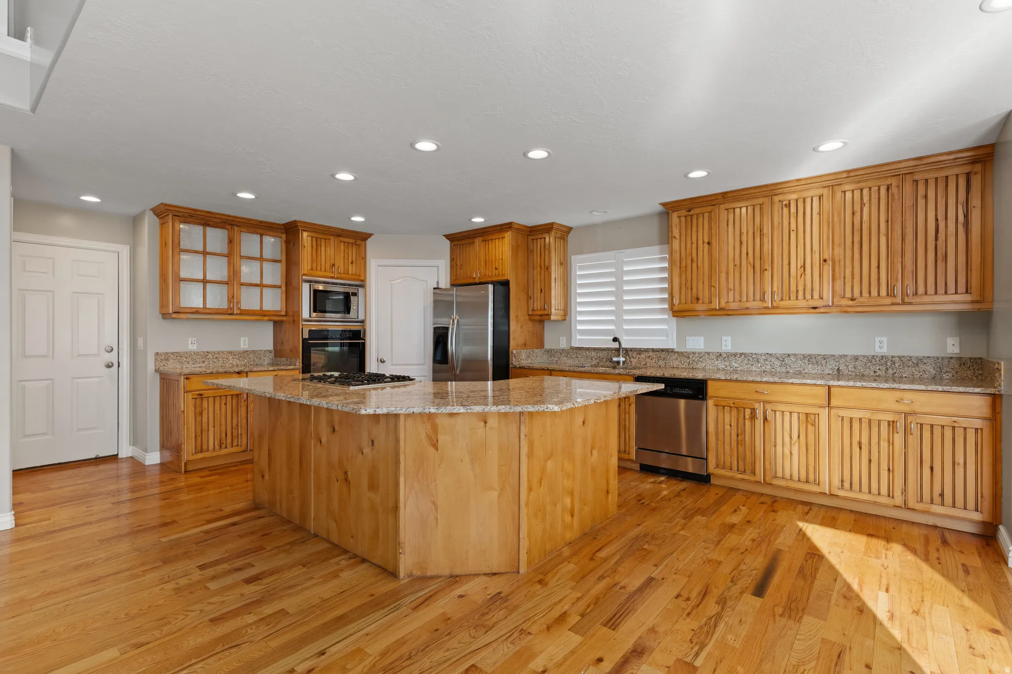 Kitchen featuring natural wood cabinetry, granite countertops, a large center island, stainless steel appliances, and recessed lighting