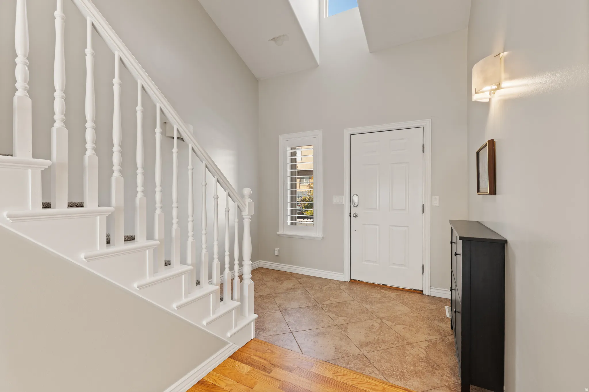 Vaulted ceilings, skylight, and a white staircase with turned balusters