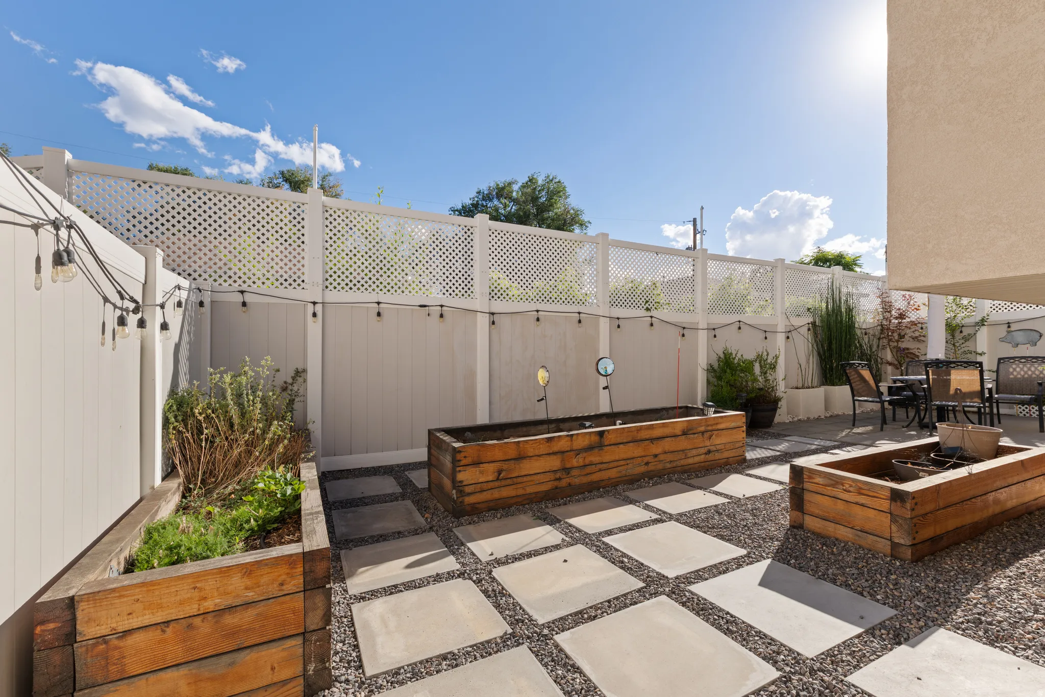 Private outdoor patio featuring large square pavers, gravel ground cover, and built-in wood planters