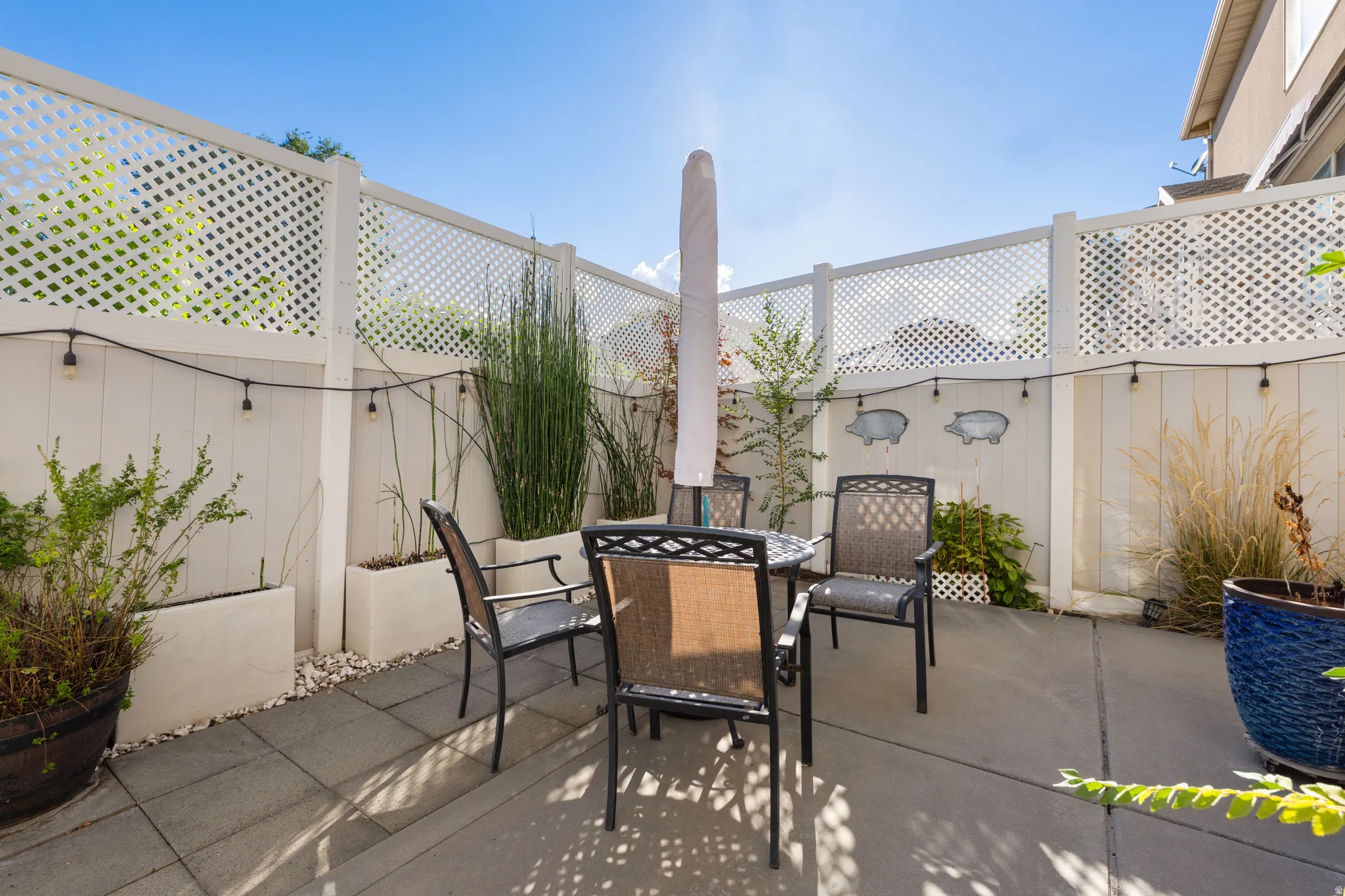 Paved patio area featuring privacy lattice fencing, string lighting, and built-in planters