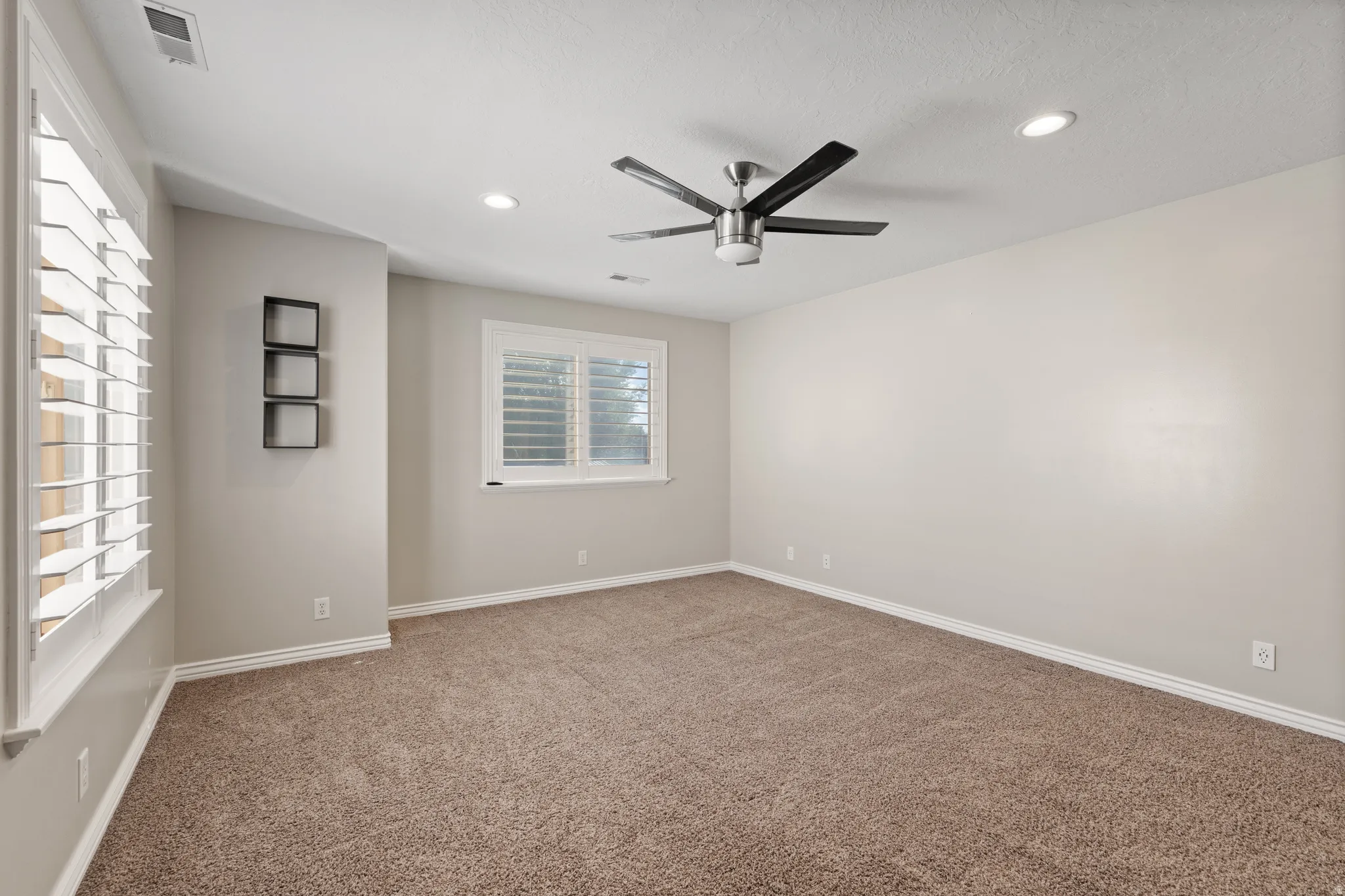 Recessed lighting, ceiling fan, carpeting, window with plantation shutters, neutral wall color