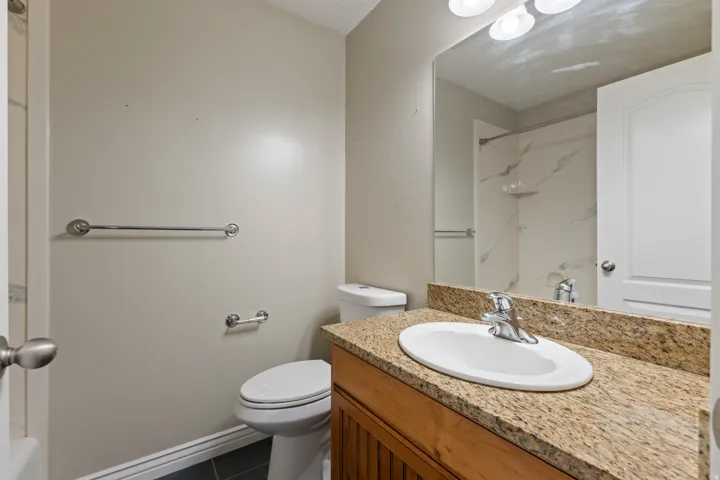 Wood-finish vanity with a granite-style countertop and undermount sink