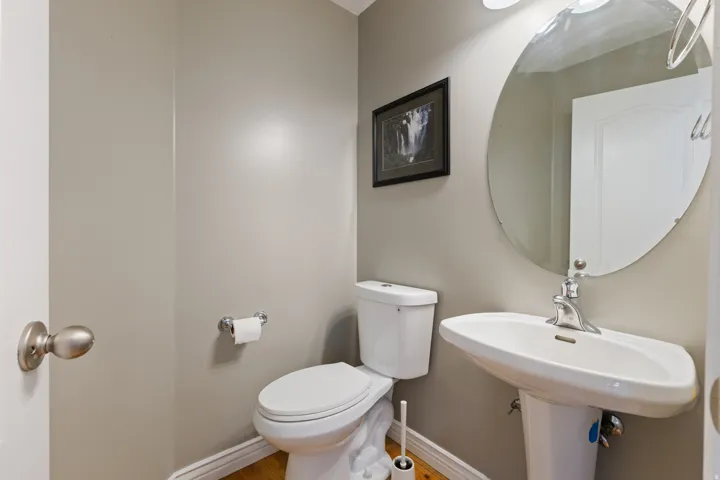 Pedestal sink with chrome faucet, oval wall mirror, and neutral wall color