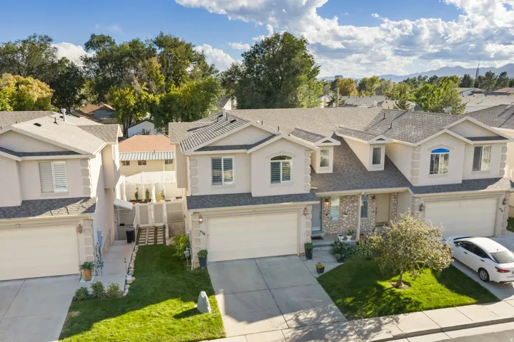 Stucco exterior with stone accents, attached garage, and dormer windows