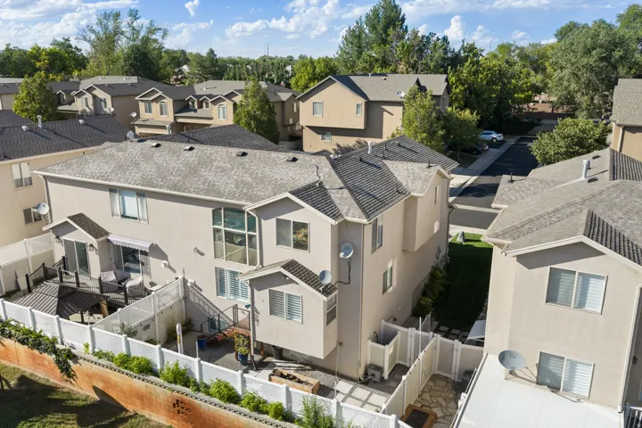 Stucco exterior residence featuring a multi-level composite deck, white vinyl fencing, and a paved patio area