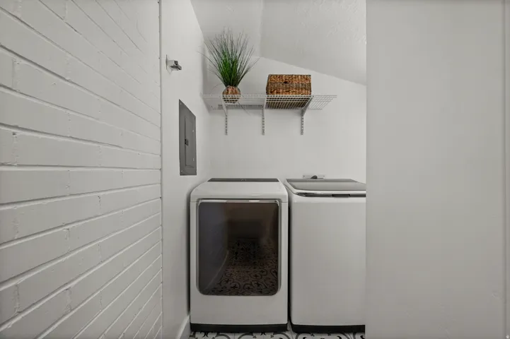 White painted brick wall, patterned floor tiling, and wall-mounted shelving
