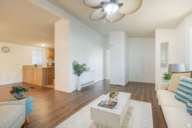 Wood-finish flooring throughout, white painted walls, and a ceiling fan with integrated lighting
