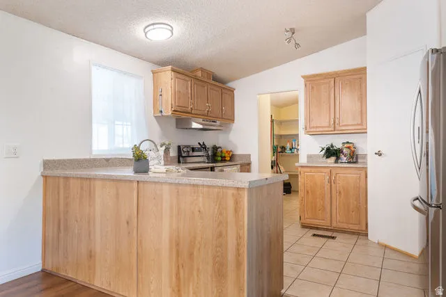 Kitchen featuring wood-finish cabinetry, light-toned countertops, and tile flooring