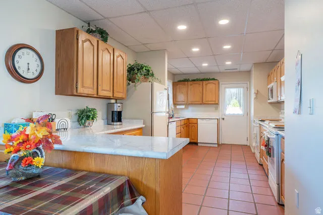 Kitchen with wood cabinetry, light-toned countertops, and tiled flooring