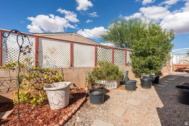 Lattice fencing with red trim, mature landscaping, gravel ground cover, and concrete stepping stones