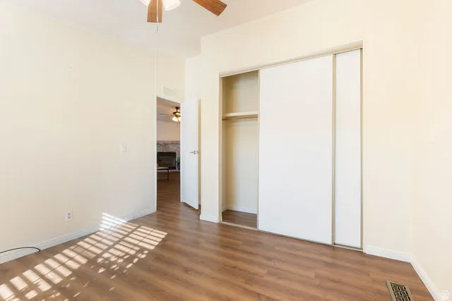 Wood-finish flooring, ceiling fan, white bi-fold closet doors, and light-toned walls