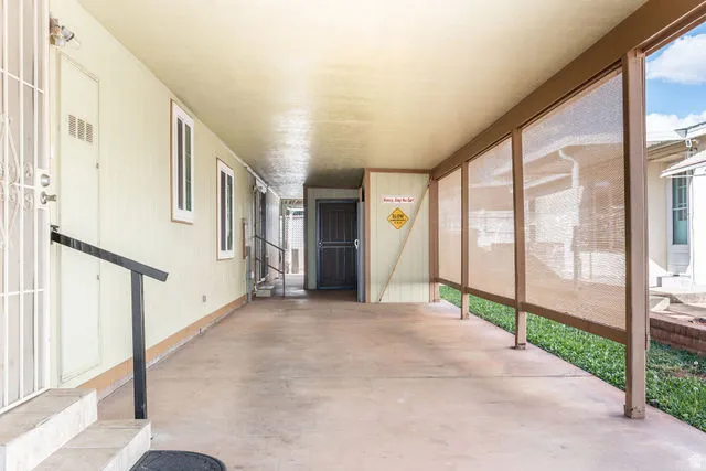Covered exterior walkway with concrete flooring and a partial screen wall