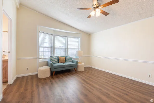 Vaulted ceiling with a ceiling fan, wood-finish flooring, and bay windows with blinds