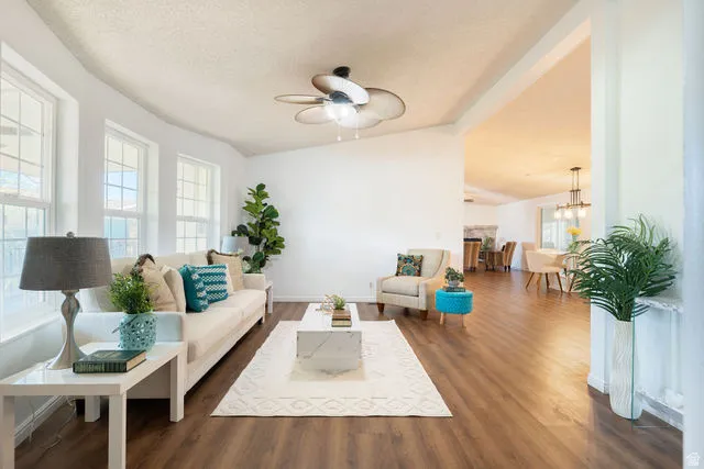 Wood-finish flooring throughout, multiple windows with white trim, and a ceiling fan with integrated lighting
