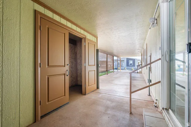 Covered outdoor walkway featuring a concrete surface and a sliding glass door