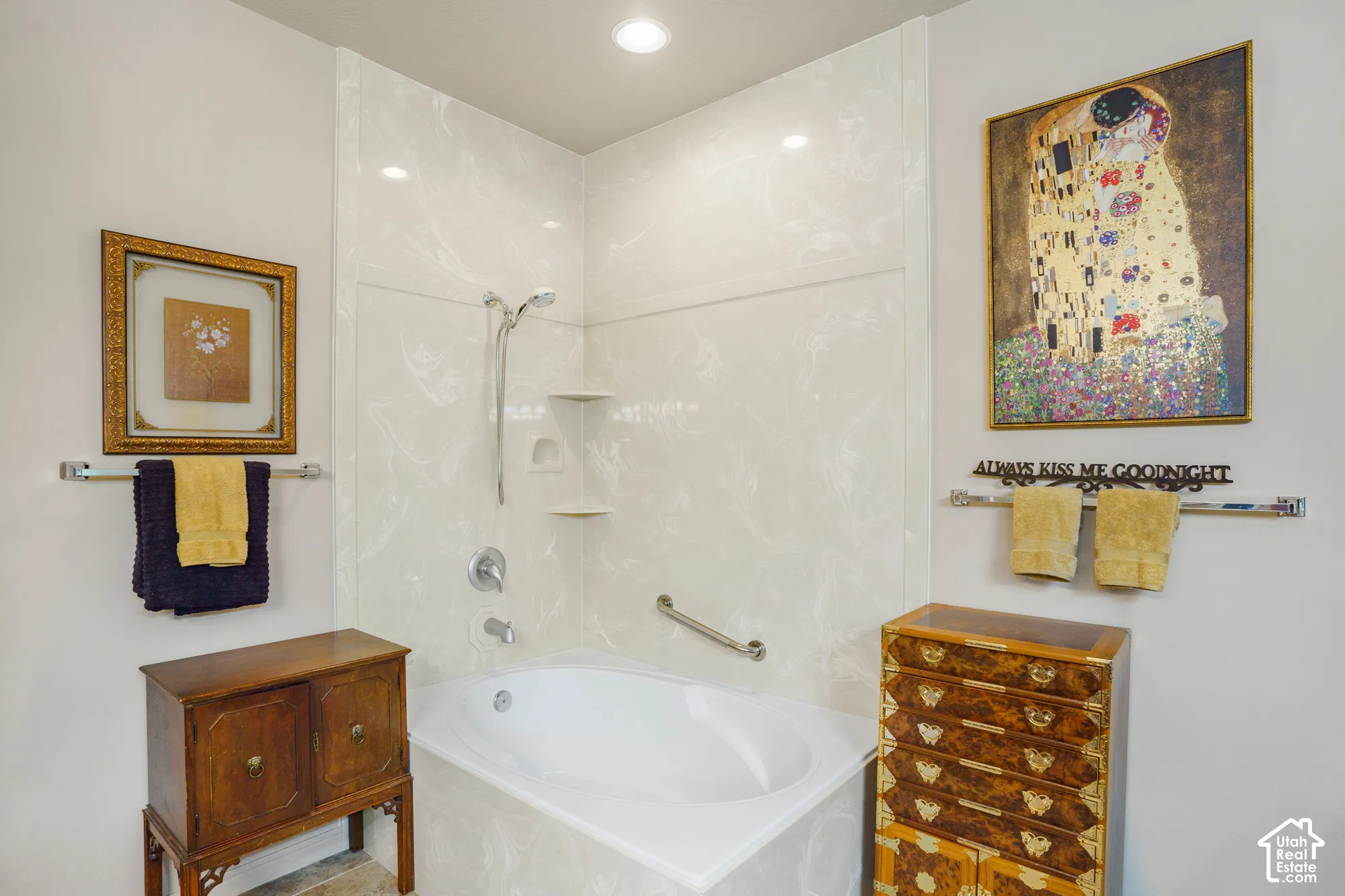 Built-in corner tub with a shower fixture, integrated shelving, and a grab bar