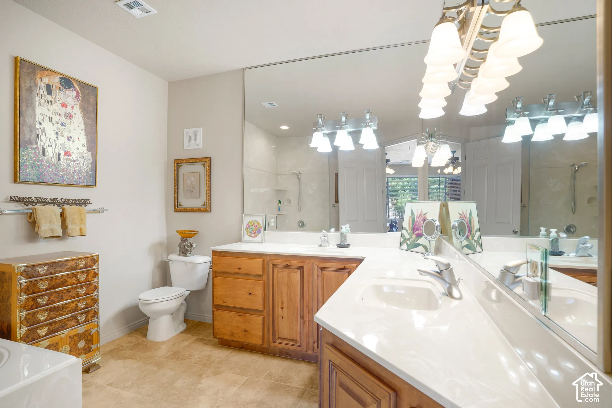 Built-in vanity with wood-finish cabinetry, dual sinks, extensive countertop space, and large wall mirror