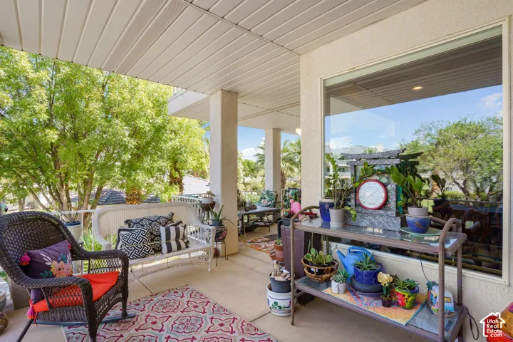 Covered patio featuring a wide window, stucco exterior, and slatted ceiling