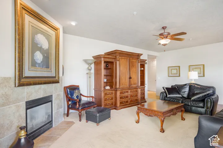 Carpeted living area featuring a tiled fireplace, recessed lighting, and a ceiling fan