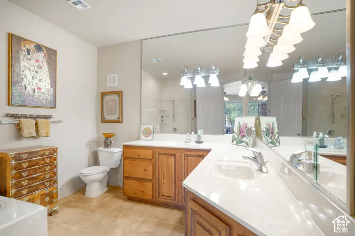 Built-in vanity with wood-finish cabinetry, dual sinks, extensive countertop space, and large wall mirror