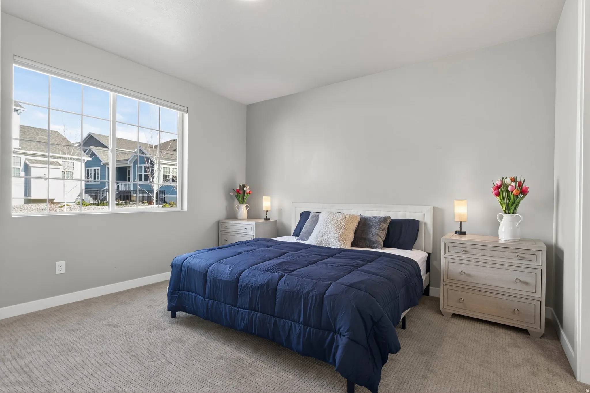 Light gray wall paint, large multi-pane window, wall-to-wall carpeting, white trim, and a white ceiling