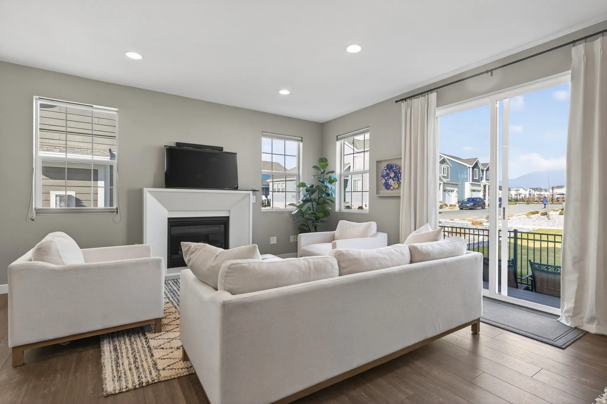 Wood-finish flooring throughout, recessed lighting, and a modern fireplace with a white surround