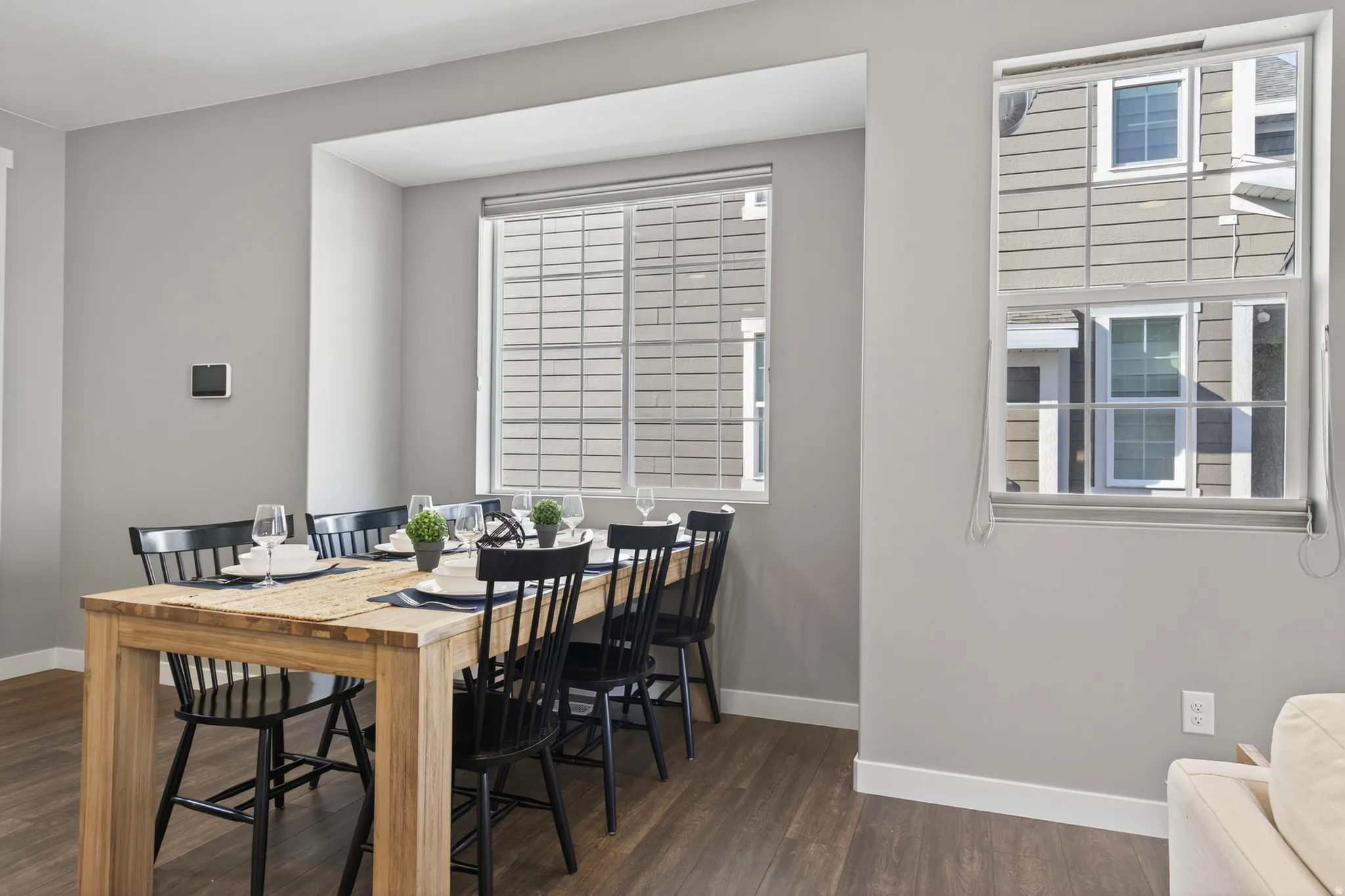 Recessed window with horizontal blinds, rich wood-finish flooring, and light gray wall paint