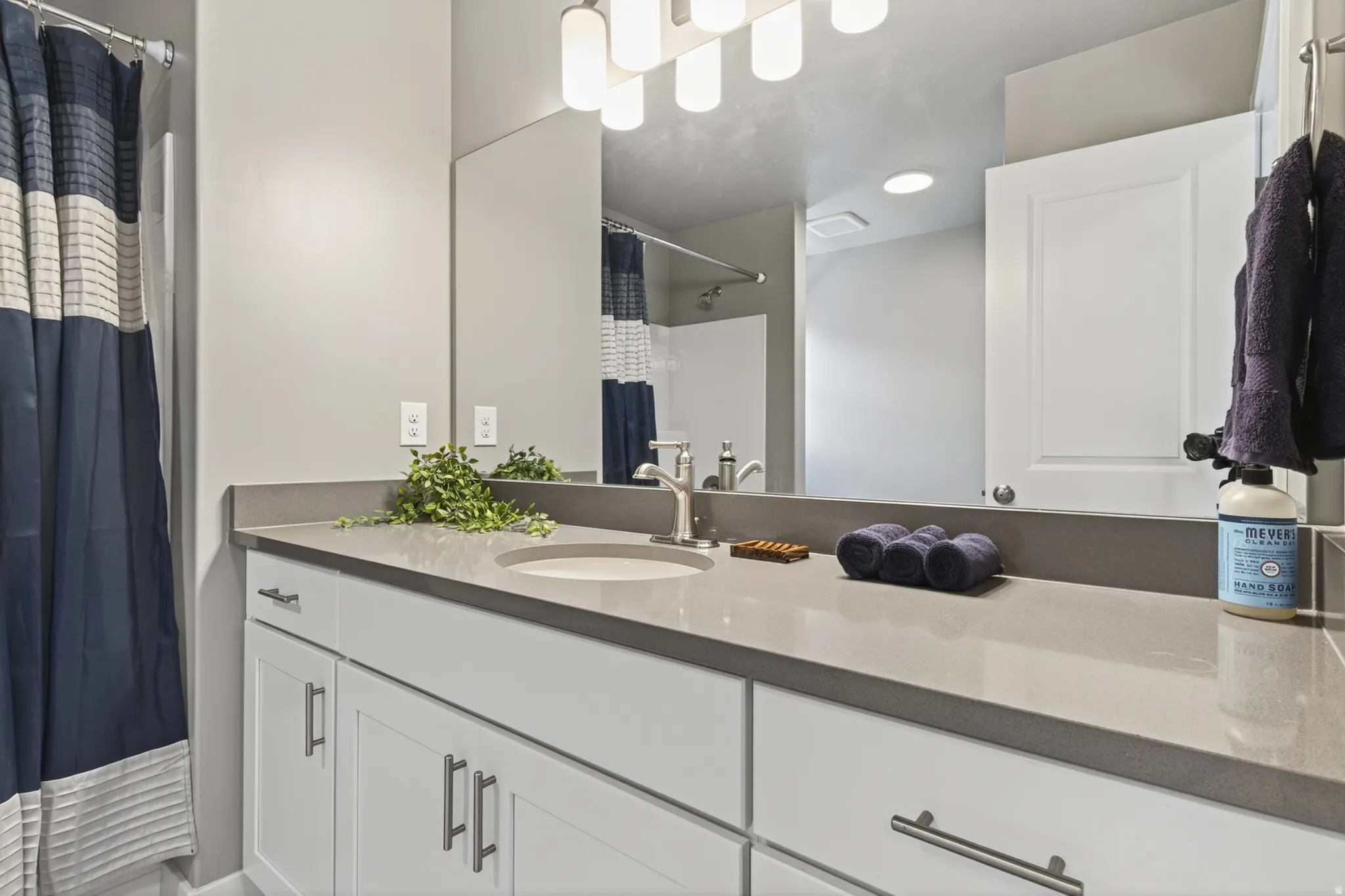 White vanity with brushed nickel hardware, integrated sink, and gray countertop