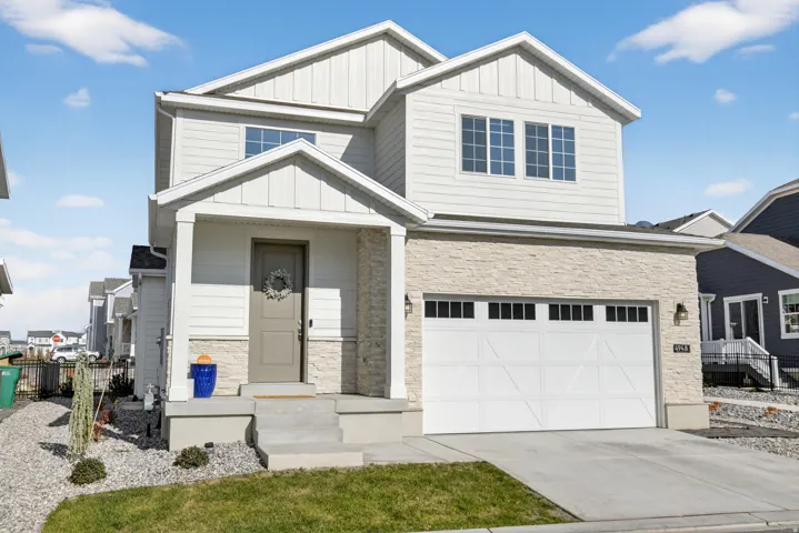 Contemporary two-story exterior featuring a prominent two-car garage, stone facade accents, and board and batten siding