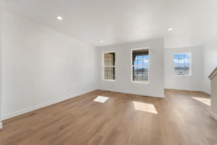Expansive room with wood-finish flooring, recessed lighting, white walls, and multiple windows