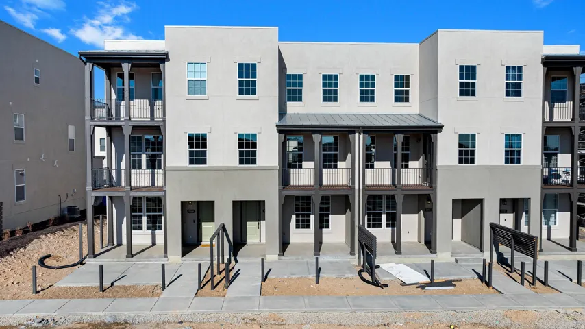 Three-story exterior with light-toned stucco and dark trim accents