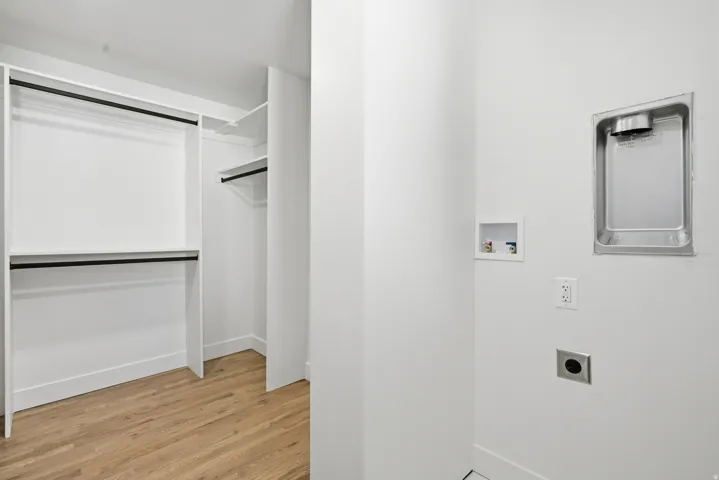 Walk-in closet with built-in shelving, hanging rods, and wood-finish flooring