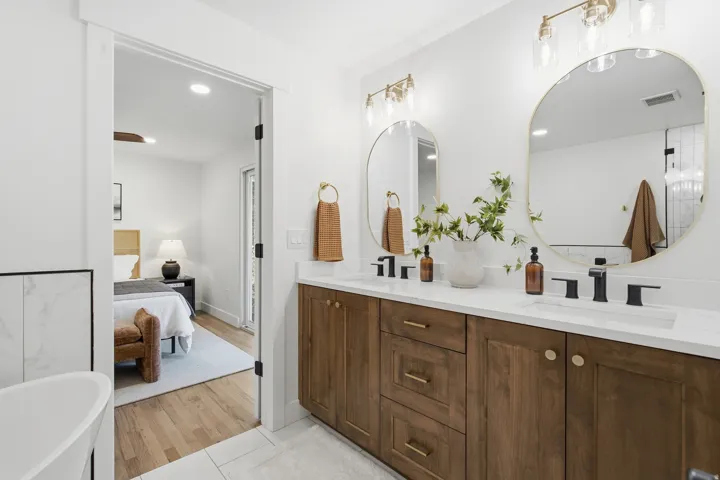 Dual vanity with wood-finish cabinetry, white countertops, and matte black fixtures